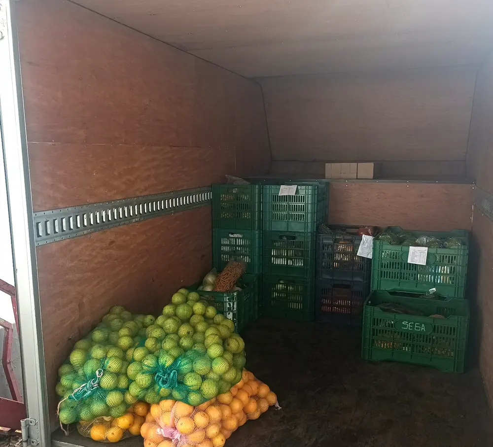 Interior de una camioneta SEGA de caja cerrada con costales de limón y naranja y cajas de verdura